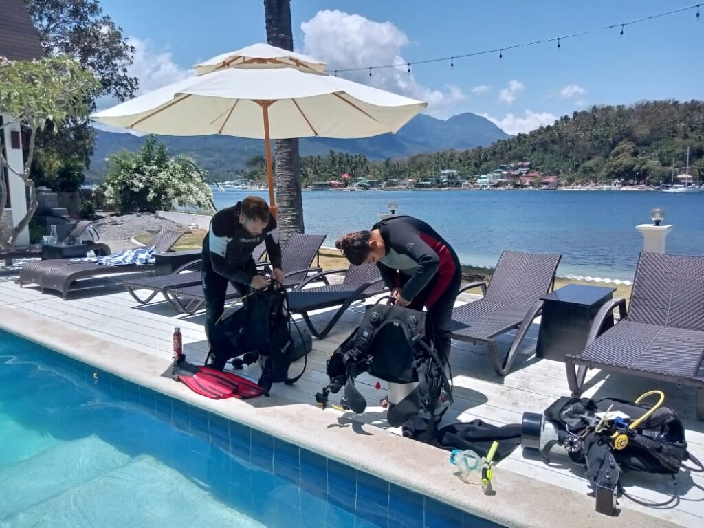 scuba diving students assembling their own equipment by the pool