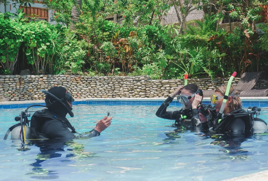 Scuba diving lesson in a serene pool at a tropical resort, surrounded by lush greenery.