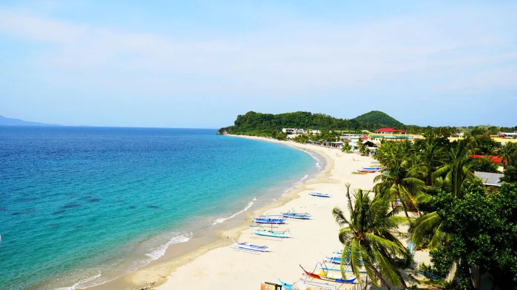 A breathtaking view of White Beach in Puerto Galera, Philippines, featuring soft white sand, crystal-clear turquoise waters, and lush tropical greenery.
